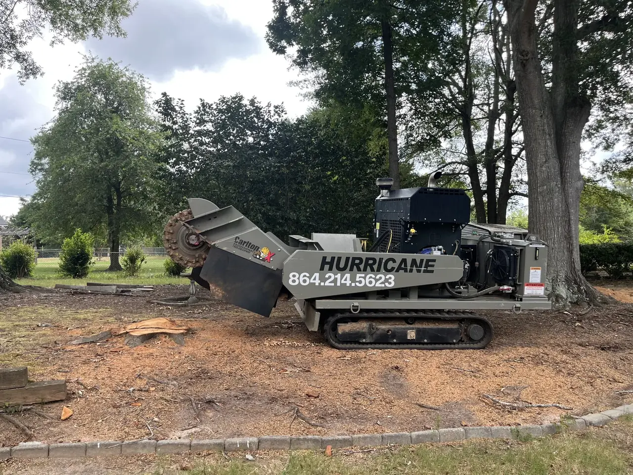 Stump grinder with the company phone number beside a cut stump